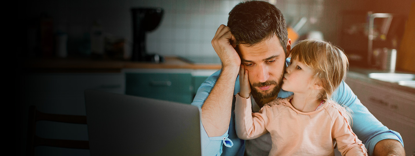 man sitting looking down with little girl on lap